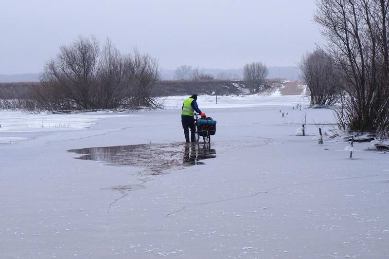 Сергей Мезенов пытается пройти по дороге, ломая лёд